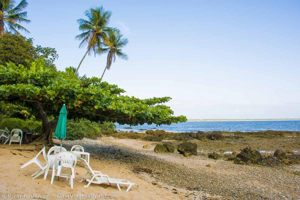 Imagem de mesas  e cadeiras nas areias da Praia das Pedrinhas na Ilha de Boipeba.